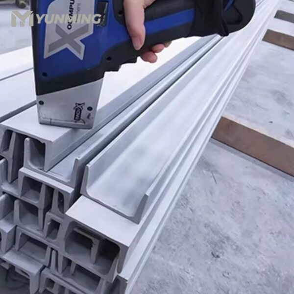 Worker inspecting stainless steel channel surface with scanner