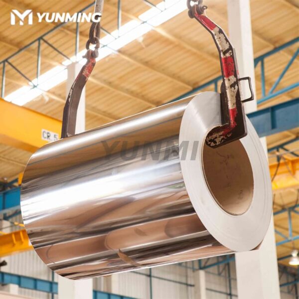 Polished stainless steel coil being lifted by crane in factory